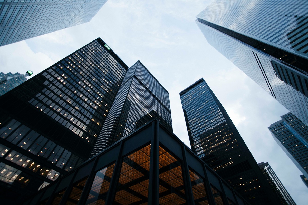 Looking up at glass financial district towers against an overcast sky